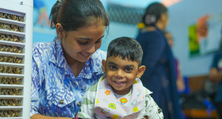 A girl looking at a smiling little boy sitting on her laps